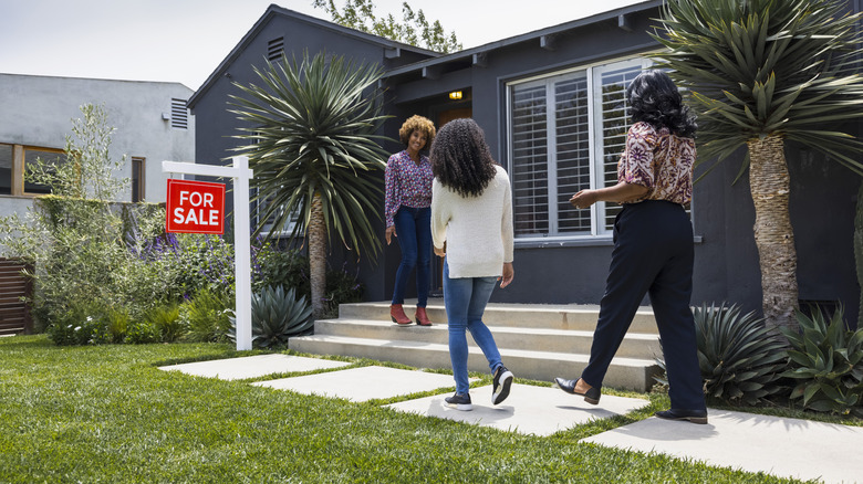 Three women near a for sale property