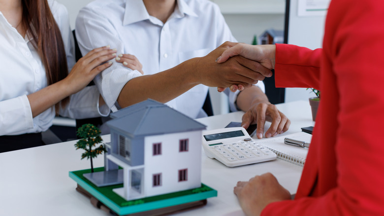 Couple shaking hands with real estate broker