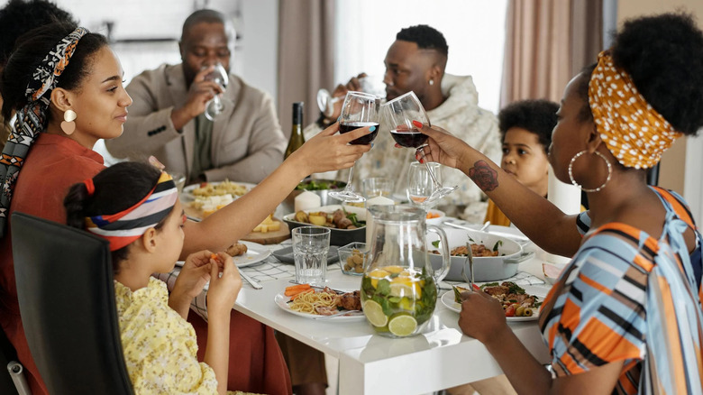 A Black family drinking wine at dinner