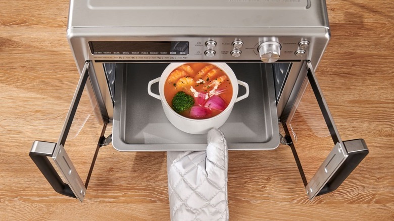 person removing pot of soup from Flexify with oven mitt