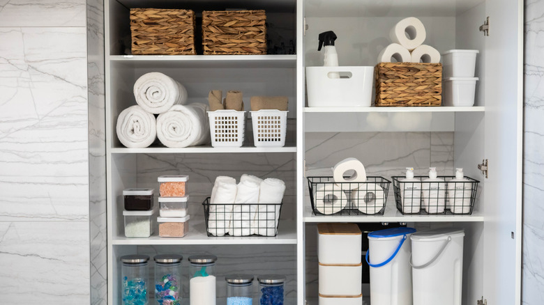 A neat everything closet filled with baskets, white bins, and extra home supplies