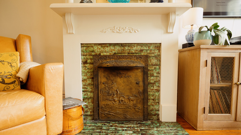 White fireplace with green tiles and iron cover