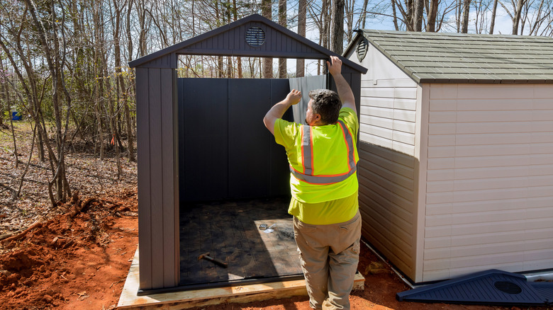 Man assembling a resin shed in his yard