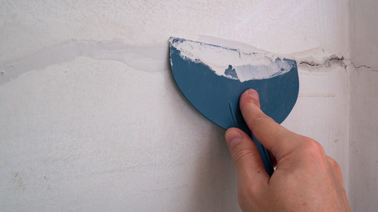 A man filling cracks in a concrete basement wall