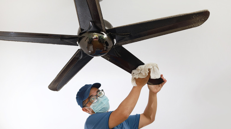 Man cleaning ceiling fan