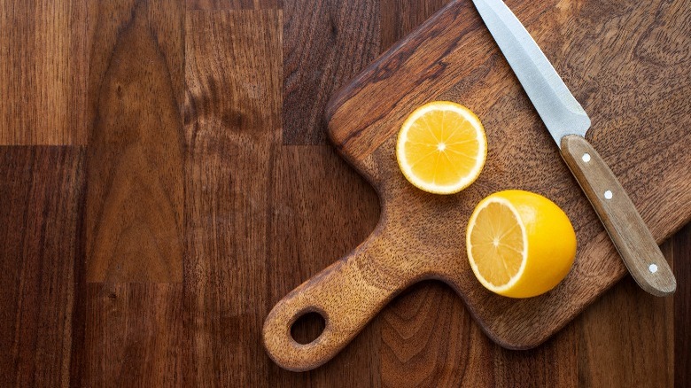 halved lemon and knife on wood cutting board