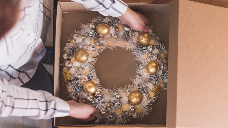 person placing wreath in box