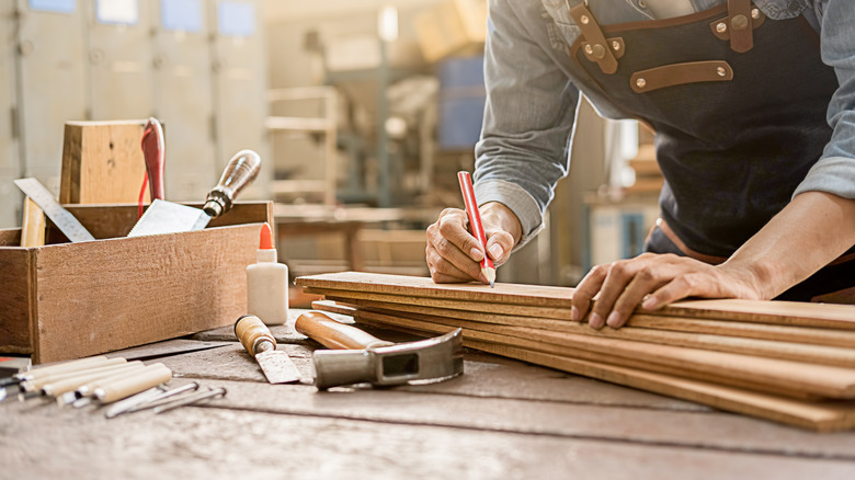 Person measuring wood for cutting