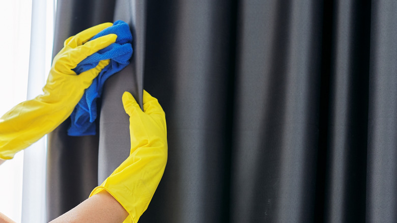 Woman with glooves cleaning curtains