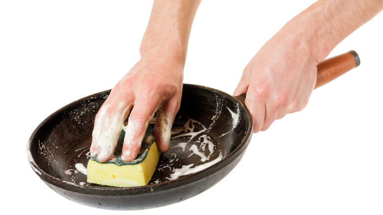 man washing pan with sponge