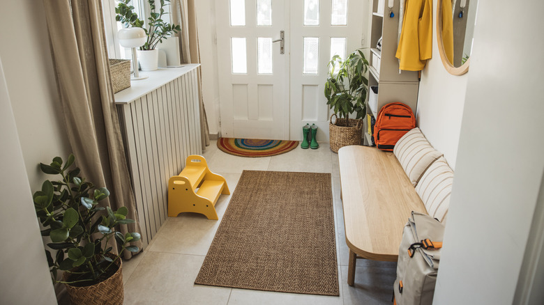 A family entryway, featuring a bench, storage, and a woven rug