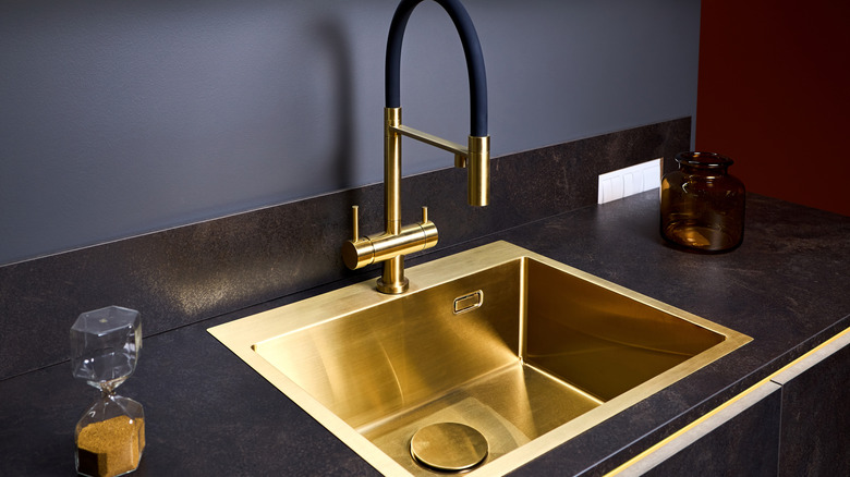 A gold sink contrasting against a black countertop in a residential kitchen.