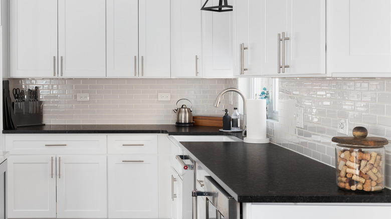 Black countertops next to white cabinets in a residential kitchen