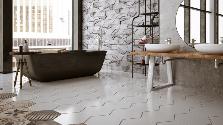 A modern bathroom has hexagonal tiles in different patterns on the floor and various textures on the walls