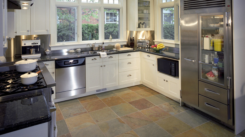 Textured tile floor in a modern kitchen with white cabinets.