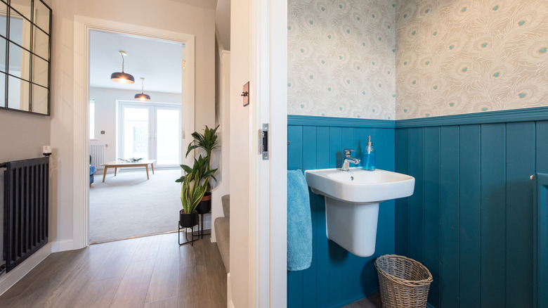 A bathroom has blue walls with pale wallpaper.