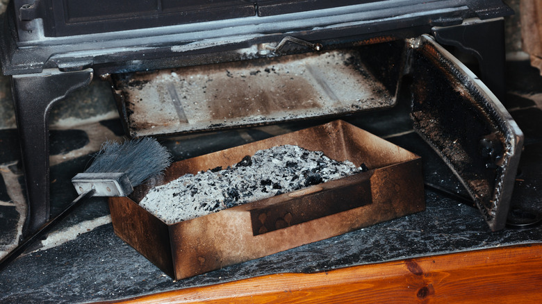 ash pan removed from fireplace with broom for cleaning beside it