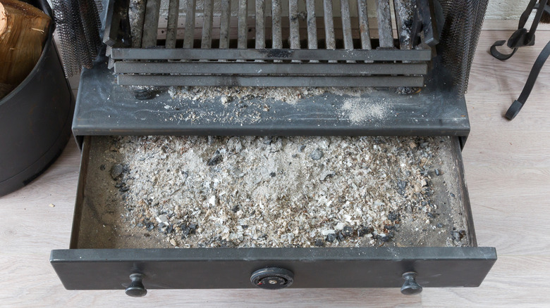 open ash pan of fireplace showing ashes collected