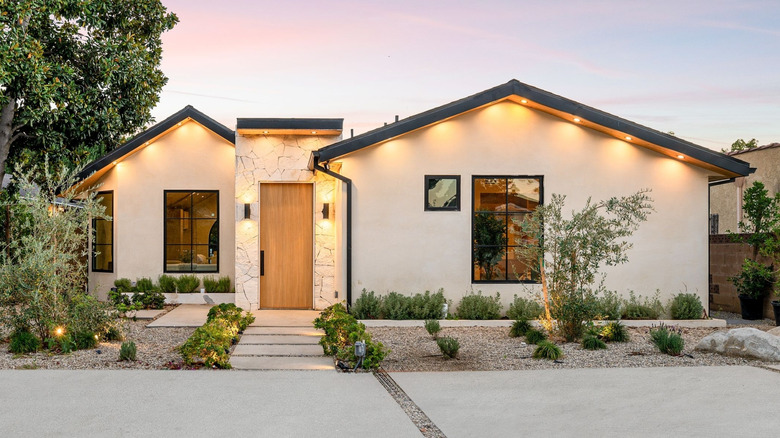 A modern white style home with black roof and sconce lights