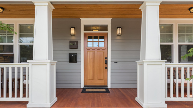 A front porch with a wood door and a black lantern wall sconces