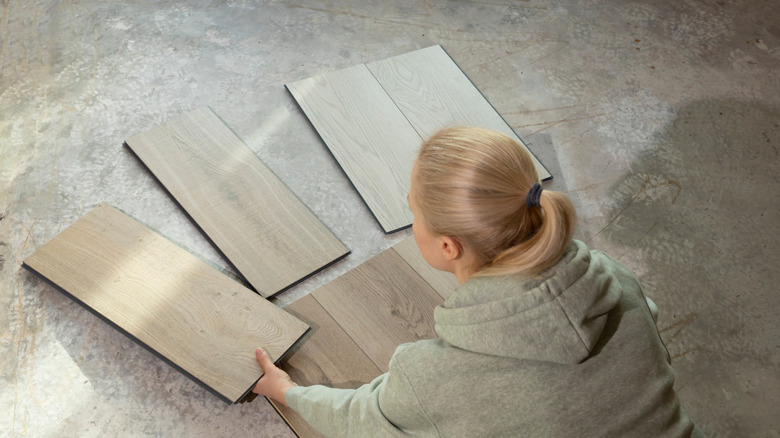 A woman examines vinyl tiles on the floor