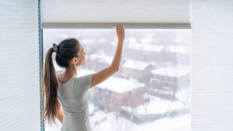 Woman lowers cellular blinds manually