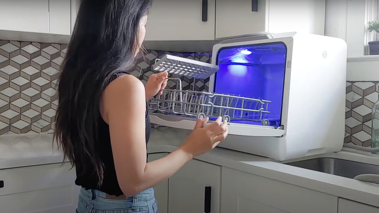 woman loading countertop dishwasher