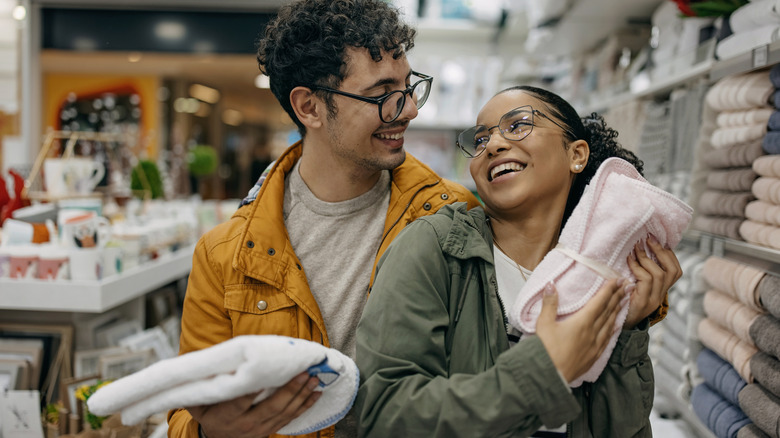 Couple smiling while holding towels in a store