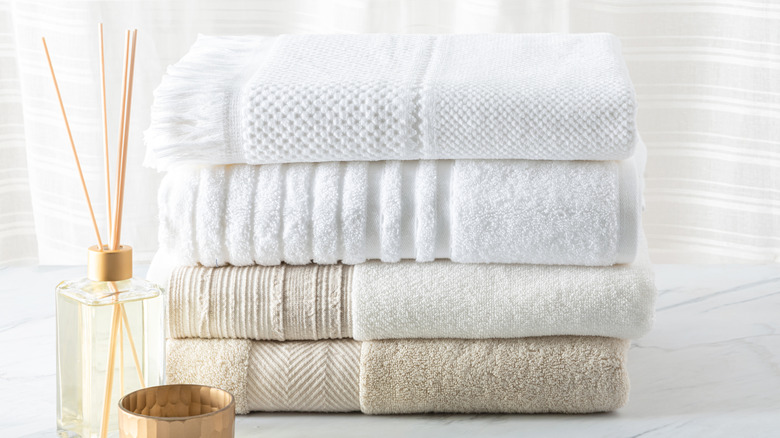 Collection of neutral-colored bath towels and a reed diffuser