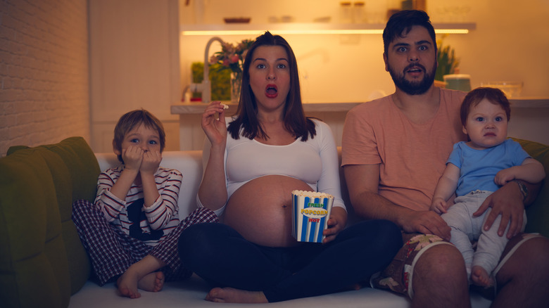 couple with kids watch tv