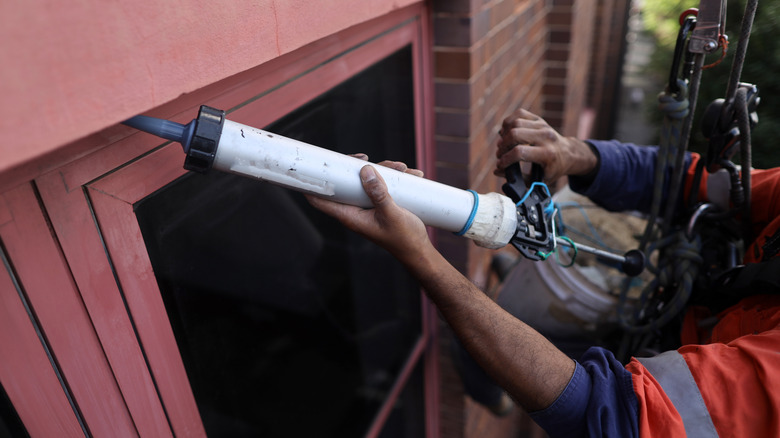 Person caulking exterior window