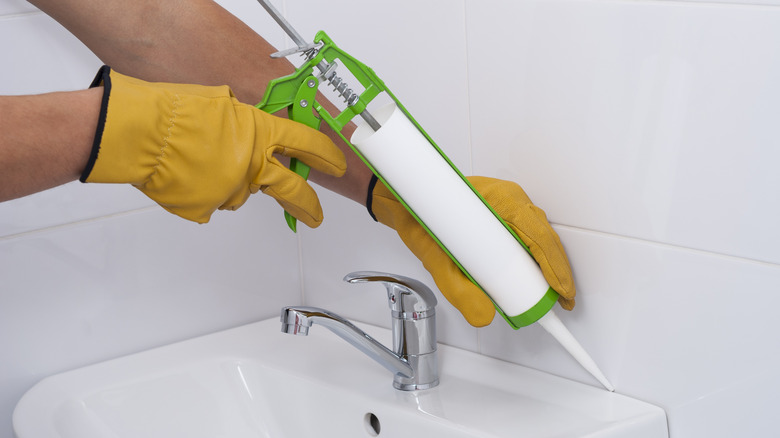 Person sealing bathroom sink