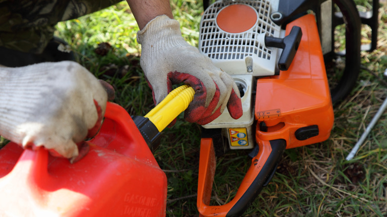 person filling chainsaw with fuel