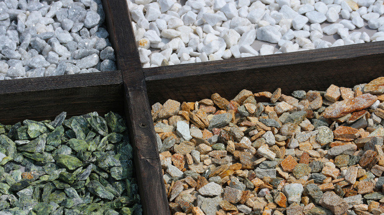 Gray, green, brown, and white gravel is separated by planks of wood