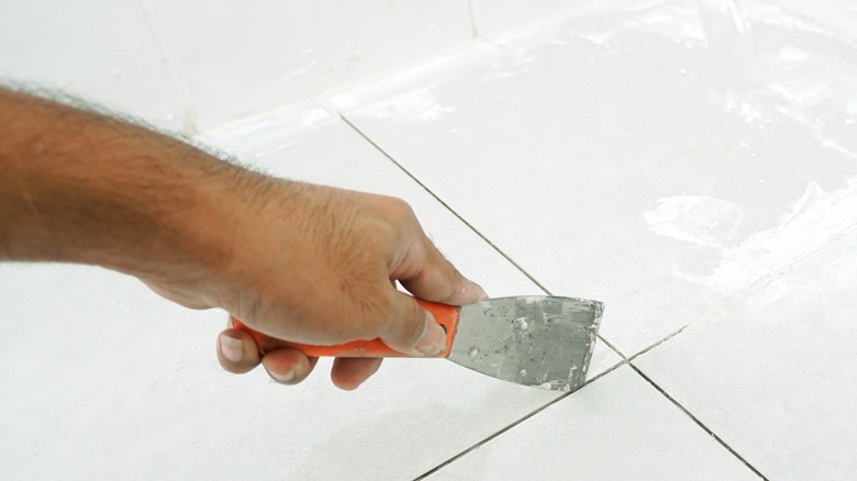 Man's hand applying tile grout 