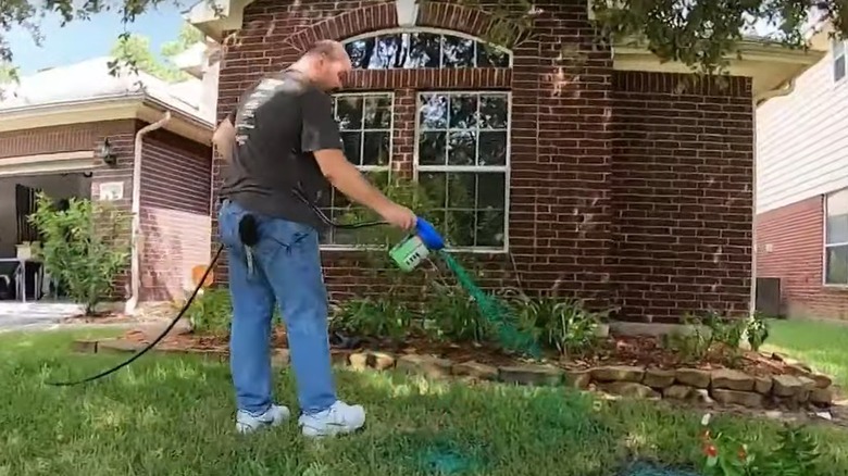 man spraying liquid grass