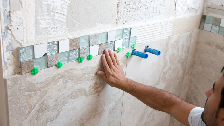 person fixing tiles on wall