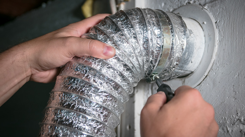 Hands installing aluminum dryer duct