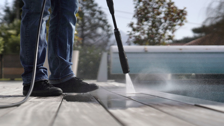 person power washing a deck 