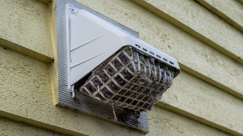 Outdoor dryer vent clogged with dust, dirt, and debris