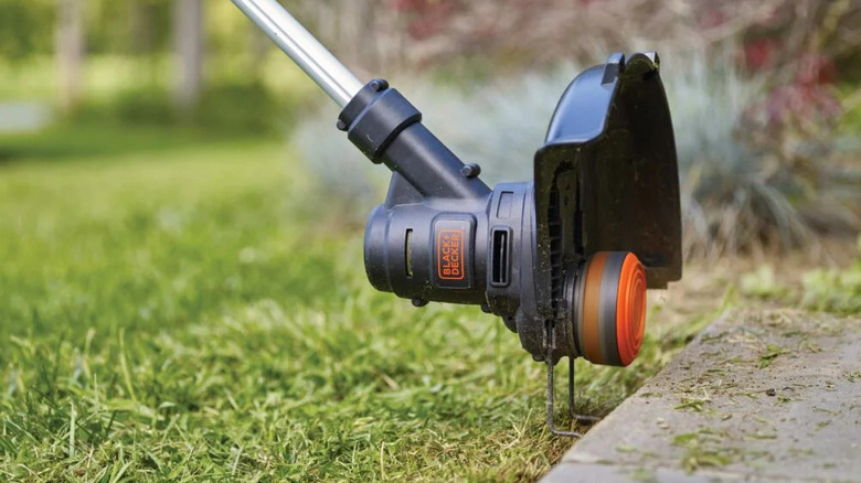 Black + Decker weed eater being used as a lawn edger