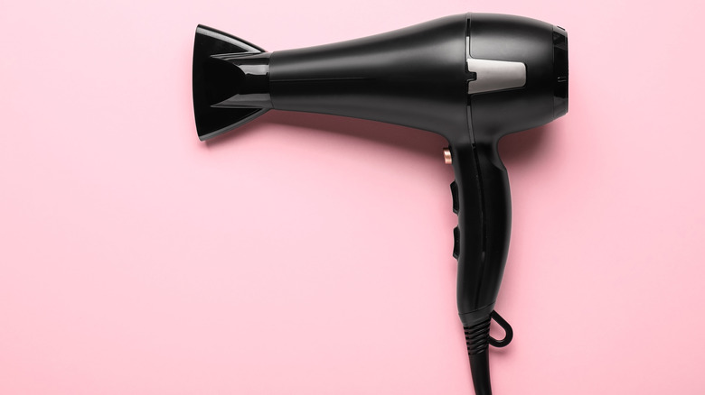 Black hairdryer on pink background