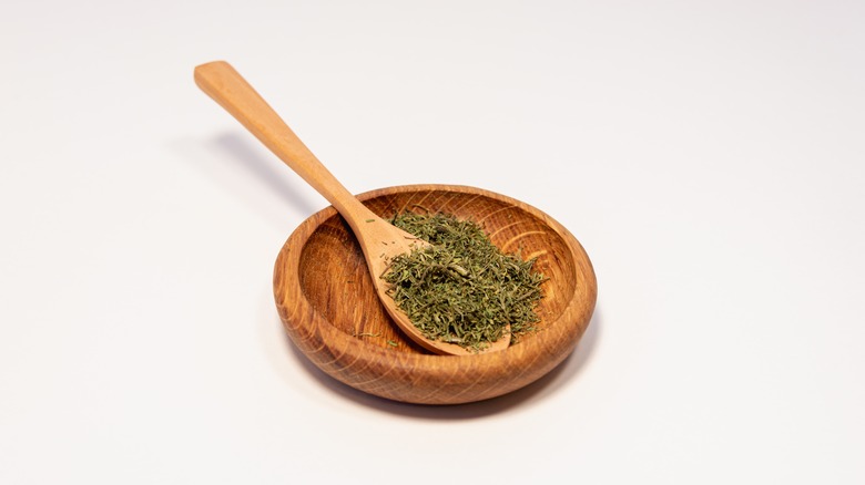 dry green dill in a cup and spoon