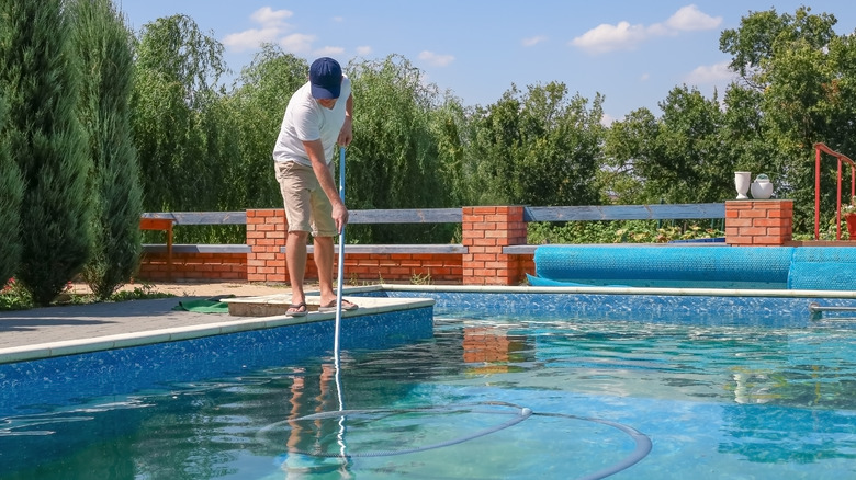 Man cleaning inground pool 