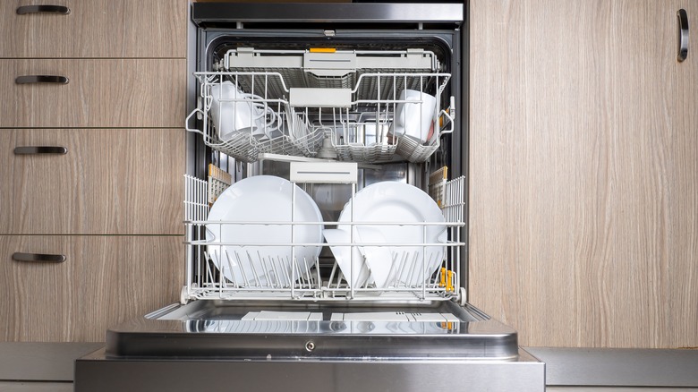 Open dishwasher installed with cabinets and drawers