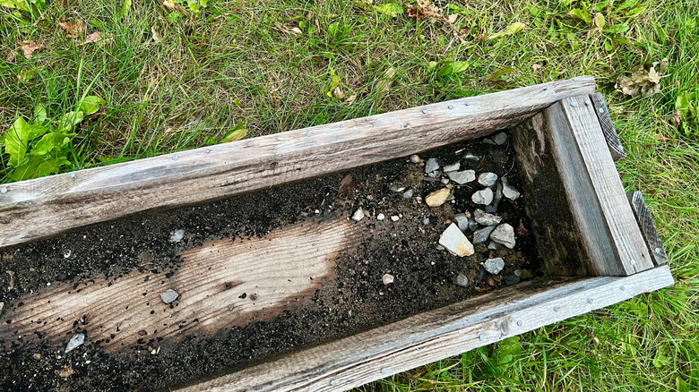 Old wooden planter box with dirt on bottom