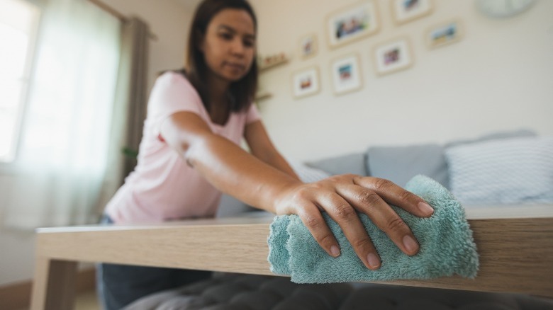 Woman cleaning table with microfiber cloth