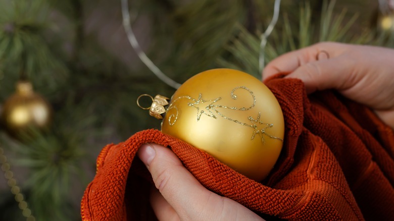 person dusting ornament with cloth