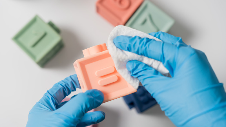 Hands cleaning plastic blocks with wipe