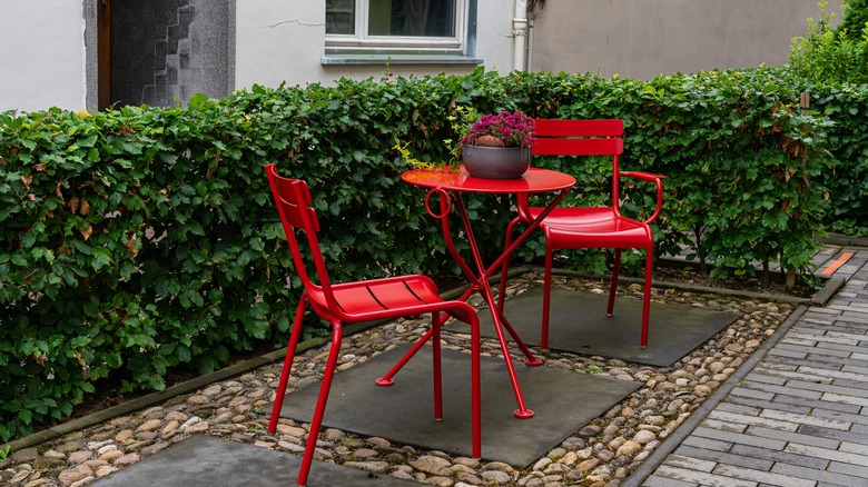 Two metal chairs and a table on gravel